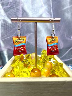 a pair of earrings with fruit on them in a bowl filled with gummy bears