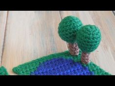 a crocheted green and blue potholder with two small trees on the top