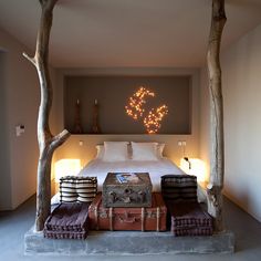 a bed sitting in the middle of a bedroom next to two trunks with lights on them