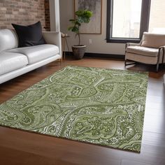 a living room filled with white couches and a green rug on top of a hard wood floor