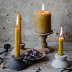 three lit candles sitting on top of a wooden table next to other items and accessories