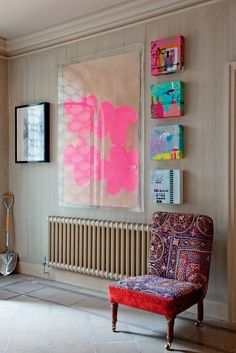 a living room filled with furniture and paintings on the wall above it's radiator