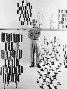 a black and white photo of a man standing in front of artwork