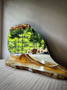 a mirror sitting on top of a wooden table next to a tree branch and potted plant