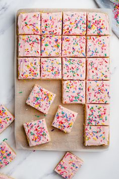 sprinkles on top of pink frosted cake next to small pieces of cake