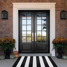 a black and white striped rug in front of a door with two pumpkins on it