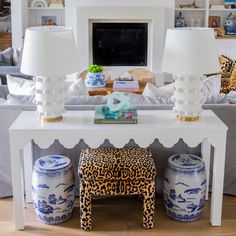 a living room with white furniture and blue and white vases on the coffee table