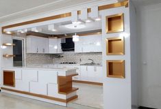 an empty kitchen with white cabinets and gold trim on the counter tops, under recessed lighting