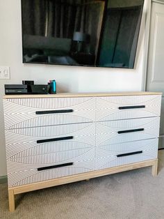 a tv mounted on the wall above a dresser in a room with carpeted flooring