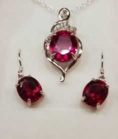 "Stunning Deep Red Ruby Necklace/Earring Set, See Video! 10x12mm/8x10mm Lab Grown Gems, 925 Sterling Silver Settings, Decorative Floral Pendant With Cubic Zirconia Accent, 18\" Sterling Chain, Ear Wires, Gift Box Included." Red Sterling Silver Jewelry Sets For Anniversary, Ruby Jewelry Sets For Gifts, Round Ruby Jewelry Sets For Gifts, Red Sterling Silver Necklace With Matching Earrings, Red Sterling Silver Jewelry As Gift For Her, Sterling Silver Gemstone Jewelry Sets As Gift, Ruby Necklaces With Matching Earrings As Gift, Ruby Necklaces With Matching Earrings For Gift, Sterling Silver Gemstone Jewelry Sets For Gifts