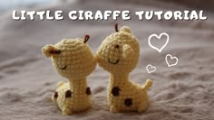 two small crocheted giraffes sitting next to each other on a bed