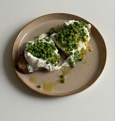 two pieces of bread topped with peas and cream