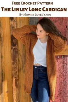 a woman standing next to a wooden wall wearing a sweater and jeans with the text free crochet pattern the linley long cardigan