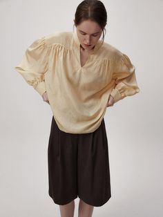 This product is a volume sleeve blouse that encapsulates modern elegance with its dramatic puff sleeves and airy silhouette. The design features a subtle V-neckline which adds a delicate touch, while the gathered details at the shoulders create an impactful volume, making it a statement piece for any wardrobe. - The blouse's voluminous sleeves are cinched at the wrists, balancing the proportions and adding sophistication to the overall design.- Made from a lightweight fabric, it provides a breezy feel and a comfortable fit for all-day wear.- The gathered shoulder detail and flowing silhouette offer a contemporary twist on the classic blouse.- Its relaxed and fluid design pairs effortlessly with both slim and wide-leg pants, making it a versatile choice for both casual and dressy occas Chic Puff Sleeve Top With Bishop Sleeves For Office, Chic Bishop Sleeve Puff Top For Office, Billowy Blouse With Smocked Cuffs And Lantern Sleeves, Elegant Blouse With Voluminous Lantern Sleeves, Billowy Lantern Sleeve Blouse With Elastic Sleeves, Office Puff Sleeve Top With Balloon Sleeves For Spring, Chic Blouse With Bishop And Elastic Sleeves, Chic Puff Sleeve Top With Bishop Sleeves, Elegant Tops With Blouson Sleeves