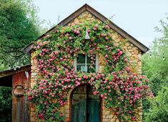 an old stone building with pink flowers growing on it