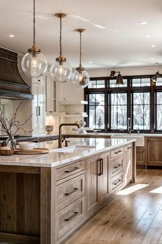 a large kitchen with an island in the middle and lots of lights hanging from the ceiling