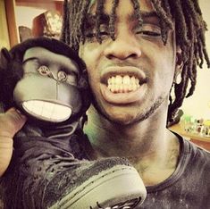 a man with dreadlocks is holding a stuffed gorilla doll in his arms and smiling