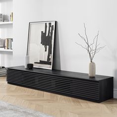 a black shelf sitting in the corner of a room next to a vase with a plant on it