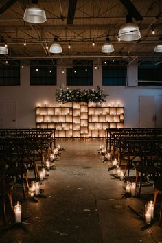 an empty church with rows of chairs and lit candles in front of the back wall