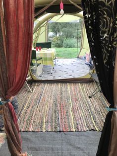 the inside of a tent with curtains open and tables set up outside in front of it