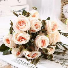 a bouquet of white roses sitting on top of a table next to a book and clock