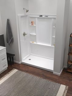 a bathroom with white walls and wood flooring next to a rug on the floor