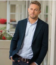 a man standing in front of a door with his hands in his pockets and looking at the camera