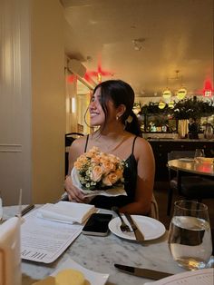 a woman sitting at a table holding a bouquet of flowers