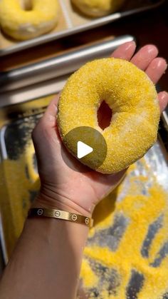 a person holding a yellow doughnut in their left hand and looking at the camera