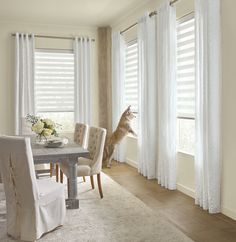 a dining room table and chairs with white curtains