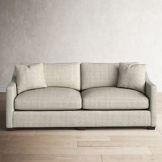 a couch sitting on top of a hard wood floor next to a white painted wall