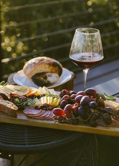 a wooden table topped with lots of food and a glass of wine next to it