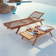 a wooden chaise lounge chair next to a pool with an open book on it