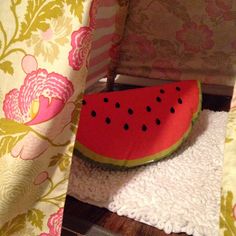 a slice of watermelon sitting on top of a bed next to a curtain