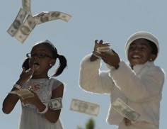 two girls in white dresses are throwing money into the air