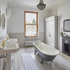 a bathroom with two sinks, a bathtub and a fire place in the corner