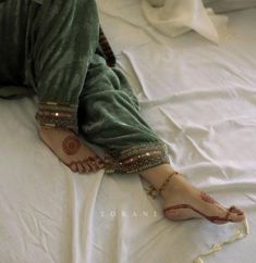 a woman laying on top of a bed covered in white sheets and barefooted shoes