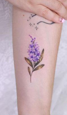 a small purple flower tattoo on the arm