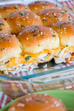 several sliders with cheese and other toppings in a glass casserole dish