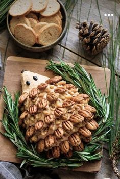 a wooden table topped with pine cones and crackers next to a bowl of cookies