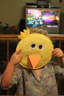 a little boy holding up a paper plate with a chicken on it's face