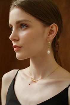 a woman wearing a necklace and earrings with pearls on her neck, looking off to the side