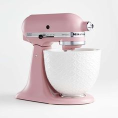 a pink mixer is sitting on a white surface