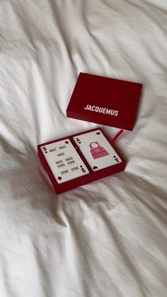 the box is open on the bed and it has two keys in it that say jacucmemus