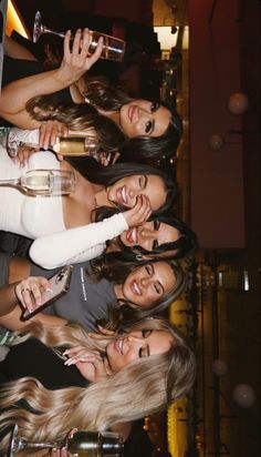 four beautiful women standing next to each other holding wine glasses