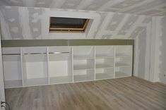 an empty room with white cabinets and wood flooring in the foreground is being painted