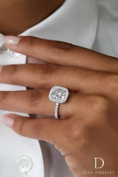 a woman's hand with a diamond ring on her finger and a white shirt