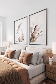 two framed pictures hang above a bed in a white bedroom with beige and brown pillows