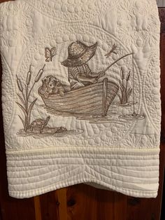 a quilted wall hanging with an image of a man in a boat