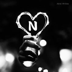 a person holding up a heart shaped object with the letter a in it's center